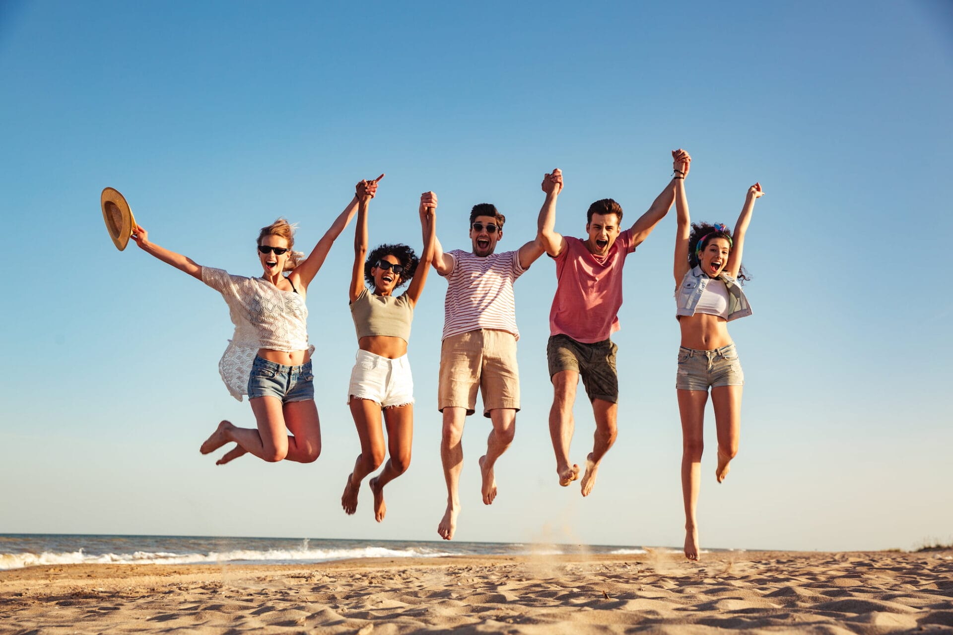 Group of young people jumping on the beach