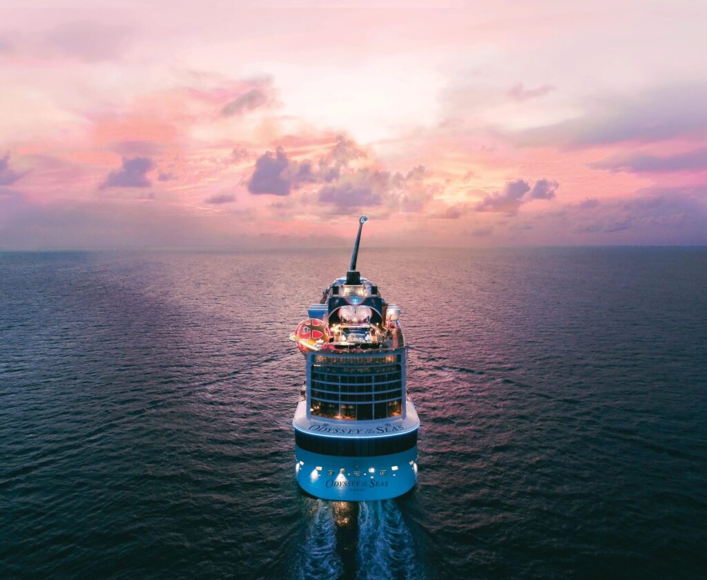 Royal Caribbean Odyssey of the Seas sailing toward the horizon at sunset