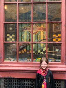 Girl in Gryffindor robes standing in front of quidditch supply shop, Diagon Alley, Universal Studios Orlando